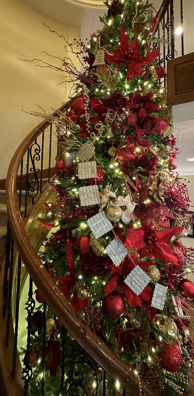 A red and gold decorated tree beside a curved staircase